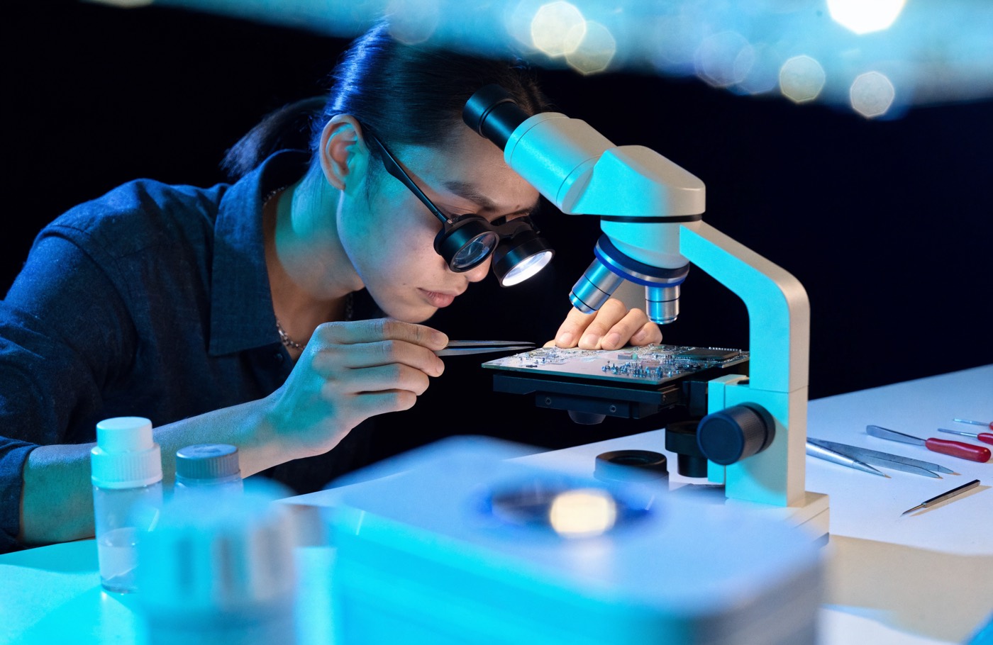 REVIV technician repairing a phone logic board under a microscope