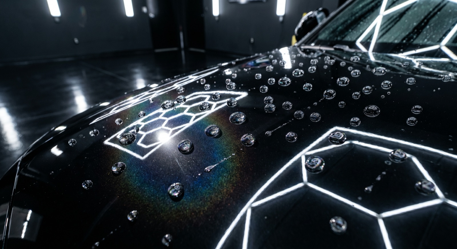 Water beading off a freshly ceramic-coated black hood under hexagonal LED studio lights